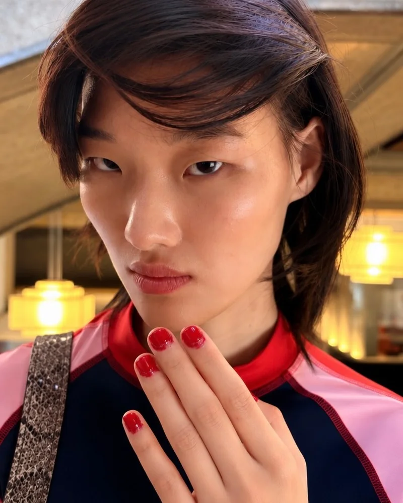 Модель за кулисами Miu Miu с короткими вишнёвыми ногтями у лица